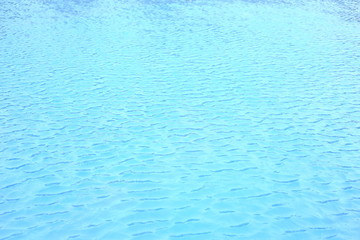 Fototapeta na wymiar wave of swimming pool water surface. open water body blown by strong wind causing wave and ripple. blue ceramic tiles floor.