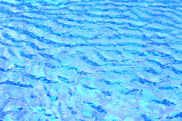 wave of swimming pool water surface. open water body blown by strong wind causing wave and ripple. blue ceramic tiles floor.