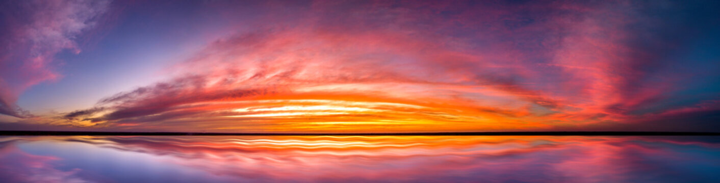 Panorama Reflection of vivid sunset sky over sea.Colorful sunrise with Clouds over ocean. 