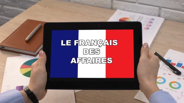 Business French application against flag on tablet in female hands, tutorial
