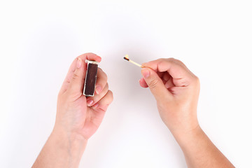 The girl lights a match from a box of matches on white background. Top view.