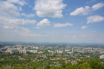 Fototapeta na wymiar Panoramic view of the city of Almaty, with industrial zone, mountains and sky with clouds. Viewed from Kok tobe, Kazakhstan.