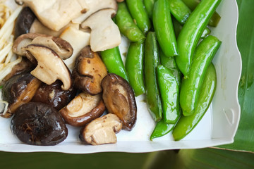 BBQ, mushrooms and potatoes in a paper dish on banana leaves in street food restaurants