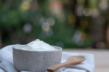 Natural homemade plain organic yogurt in ceramic bowl on wood texture background