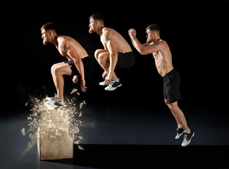 Sporty man jumping on box training at the gym