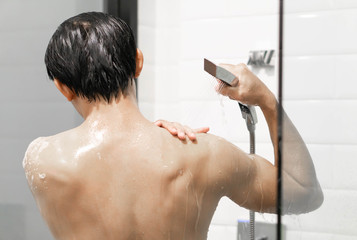 Closeup handsome asian man taking a shower in the bathroom, selective focus