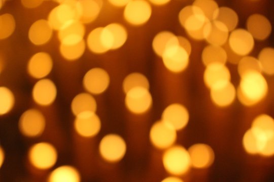 Many candles illuminate in the dark, filmed as blurred