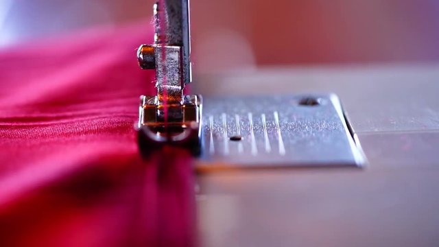 Close of of a red peice of material being sewn on an electric sewing machine