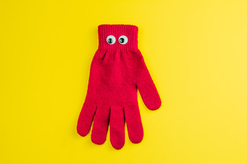 top view red  glove  with googly eyes isolated  on a yellow background