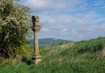 Wayside cross with cloudy sky and in the background cloister Banz