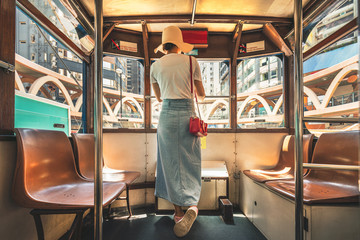 Woman wearing straw hat stand on tram in Hong Kong - obrazy, fototapety, plakaty