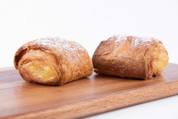 Two freshly baked puff pastry buns with powdered sugar