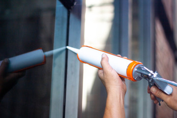 Men's hand uses silicone adhesive with adhesive to connect the mirror with aluminum.