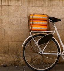 Fragment of a bicycle with decorative wheels on the trunk against the background of the wall on the street. Cropped shot, vertical, close-up, proper text space on the left, background. Concept of spor