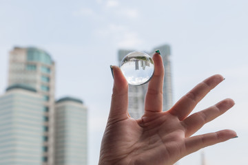 Woman hand holding a crystal ball with office building inside inverted