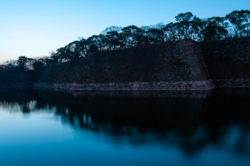 綺麗な朝焼けの大阪城の石垣と映り込み