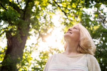 Close up portrait of senior woman by the tree looking up.
