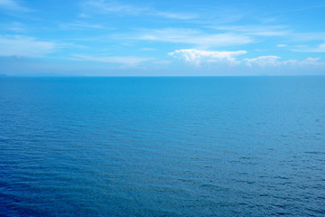 Beautiful white clouds on blue sky over calm sea with sunlight reflection