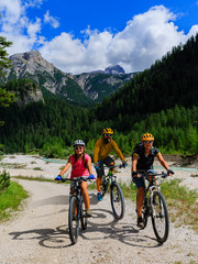 Cycling family riding on bikes in Dolomites mountains landscape. Couple cycling MTB enduro trail track. Outdoor sport activity.