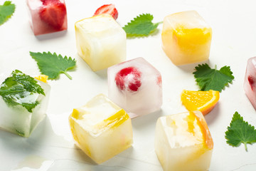 Ice cubes with fruit and mint leaves on a white stone background. Fruit ice concept, quenching thirst, summer