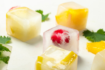 Ice cubes with fruit and mint leaves on a white stone background. Fruit ice concept, quenching thirst, summer