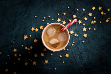 Coffee with ice and milk in a glass on a dark blue stone background with stars. Concept cooling drink, thirst, summer, starry sky, nightlife, insomnia. Flat lay, top view