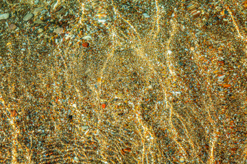 Beautiful transparent sea water with sun highlights, sandy bottom, background. Space for text.