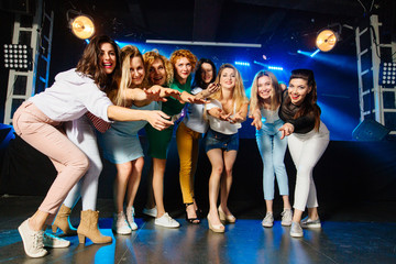 Stylish sexy bridesmaids having fun with bride standing in a row celebrating at party in night club.. Cheerful happy girls celebrate a bachelorette party of bride.