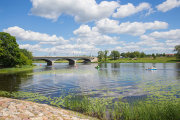 Fototapeta premium City Jelgava, Latvian Republic. River Lielupe, people are driving catamaran. Bridge and water. Jun 9. 2019. Travel photo.