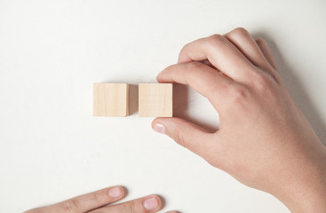 Hand holding wooden cube on a white desk.