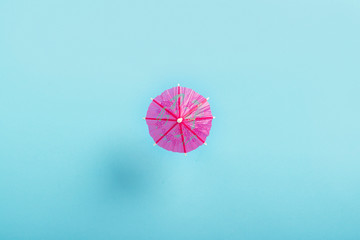 Decorative umbrella for a cocktail on a blue background. Flat lay, top view