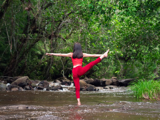 Asian woman practicing or doing yoga at the waterfall. Beautiful Landscape, Natural background, Thailand.