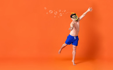 Shirtless man wearing snorkel mask doing swimming gesture