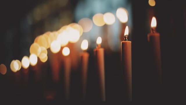 Close up footage of burning candles inside a church