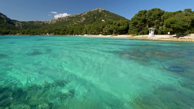 Mallorca, Spain. Sandy beach with turquoise water. Transparent water of Mediterranean Sea are covered with tiny waves. 4K