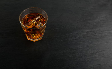 Iced Whiskey Glass on Natural Black Stone Background