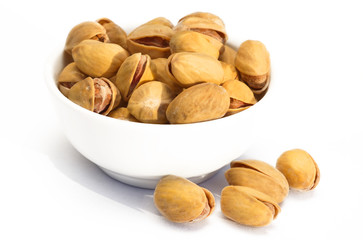Fried salted pistachios in a bowl on a white background
