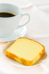 Piece of butter cake on white dish served with cup of black coffee. Times to relax concept.