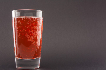 Red liquid (water) in a glass on black background with copyspace