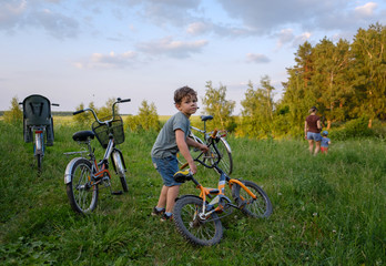 family summer bike ride.the boy holds the bike, my mother leads the younger brother in the direction of the forest by the hand. Parking paddles in nature