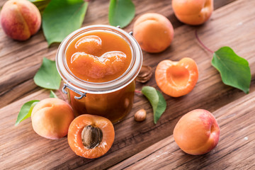Apricot jam and ripe apricots on the table.