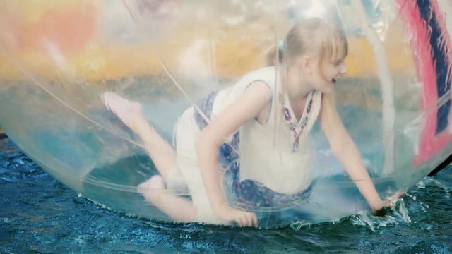 Girl have fun inside the ball that swims in the pool - summer vacation