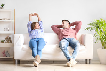 Happy young couple resting together on sofa at home