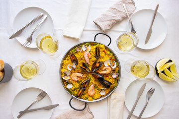 Table setting for friends meeting. Spanish paella for food friends. Top view lifestyle background.