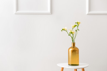 Vase with beautiful freesia flowers on table against light background