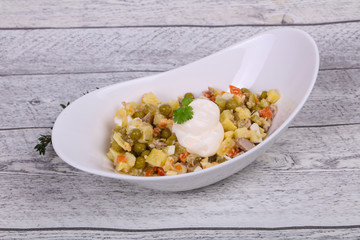 Traditional Russian salad with chicken in the white bowl