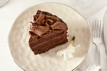 Plate with piece of tasty chocolate cake on table
