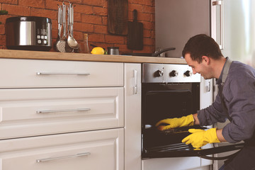 Man cleaning oven at home