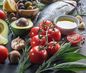 Raw dorado fish with spices and vegetables on the graphite board.