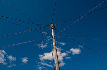 Old wooden power pole with power lines going off in different directions.